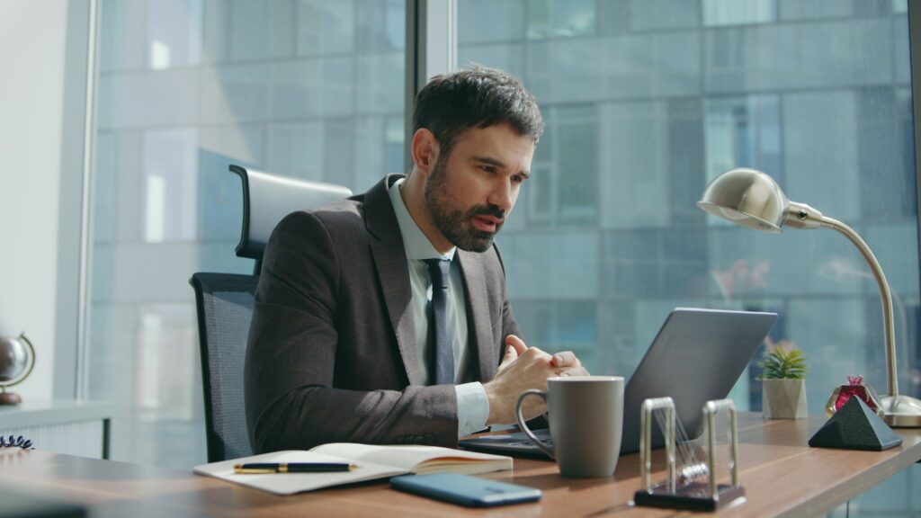 Hr talking online interview sitting office desk looking laptop. Man videocalling